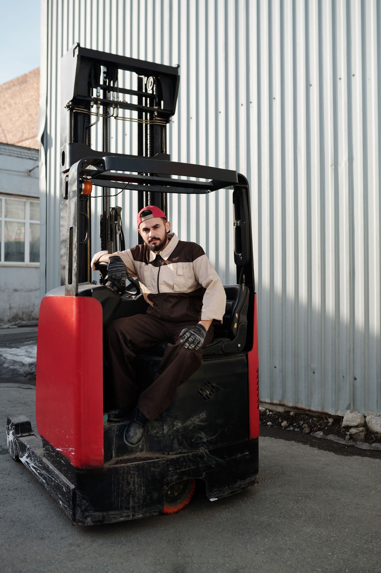 Forklift operator seated outside an industrial warehouse